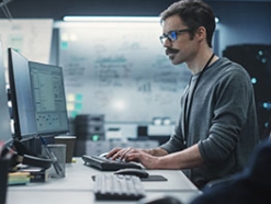 Man with a mustache and glasses working in an office 