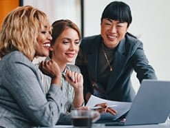 3 women gathered around a laptop